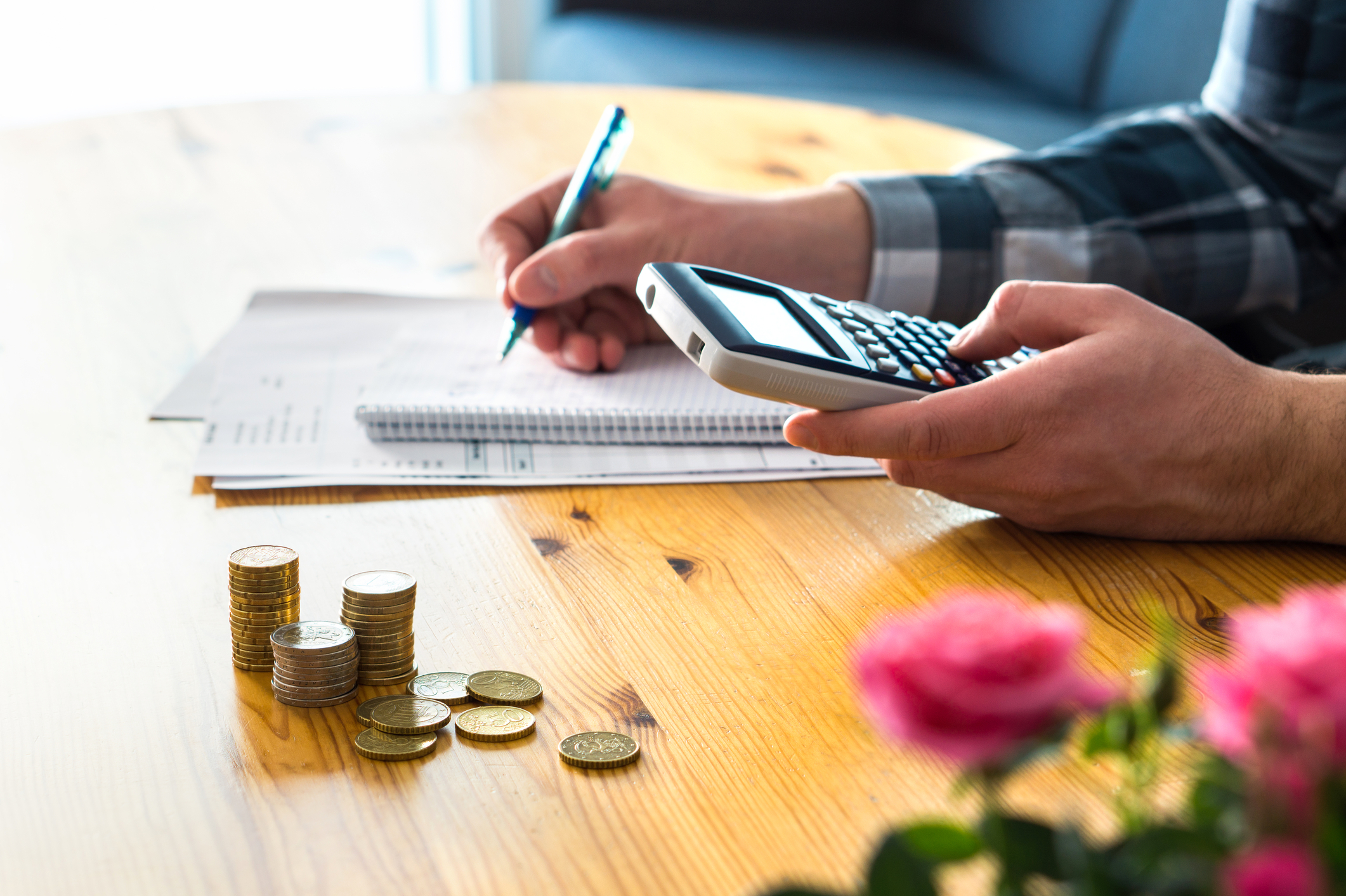 A man running through the costs of all his bills with a calculator and making notes.