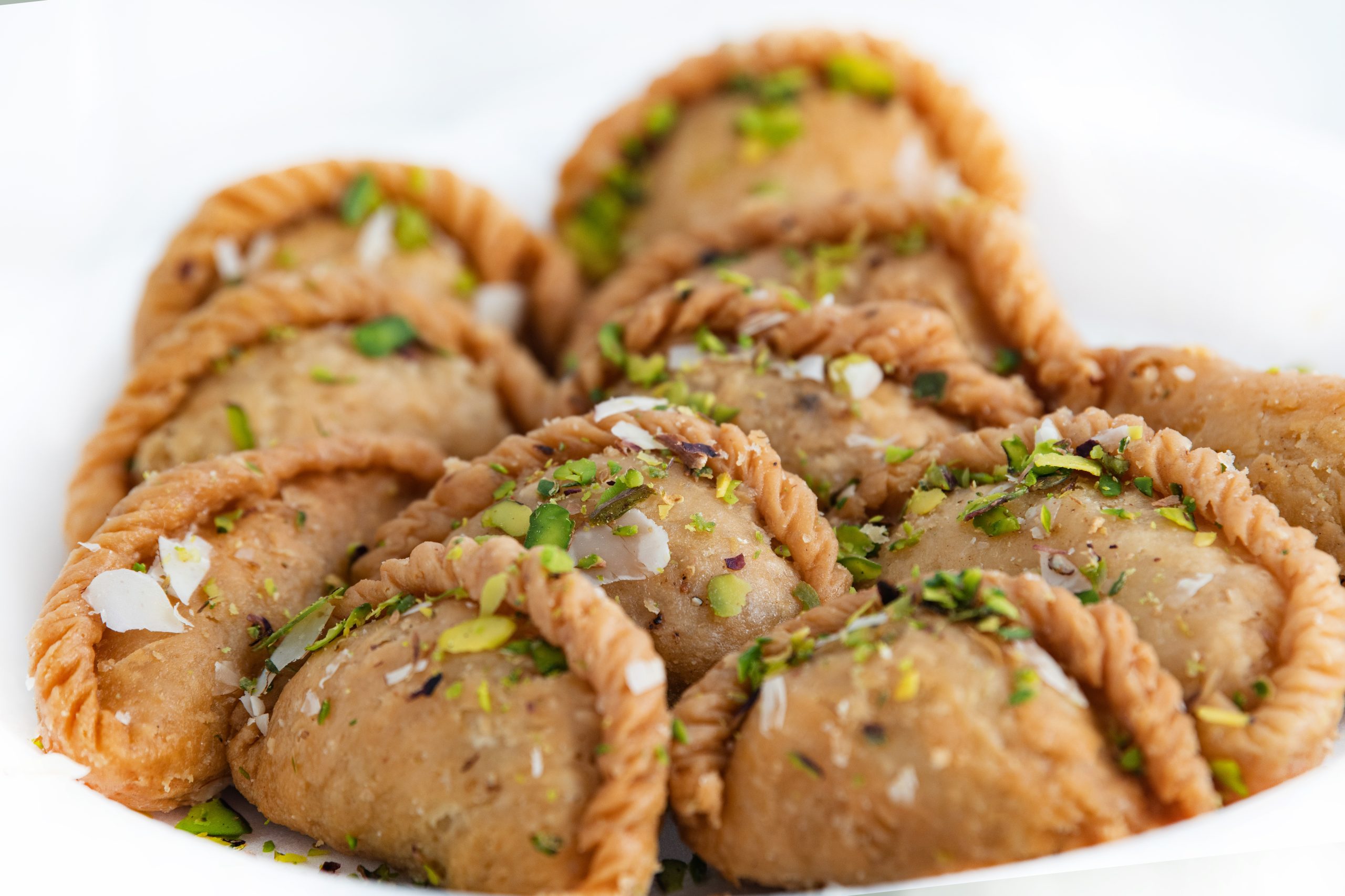 A plate of the Indian dessert gujiya, sprinkled with ground pistachios and flaked coconut.