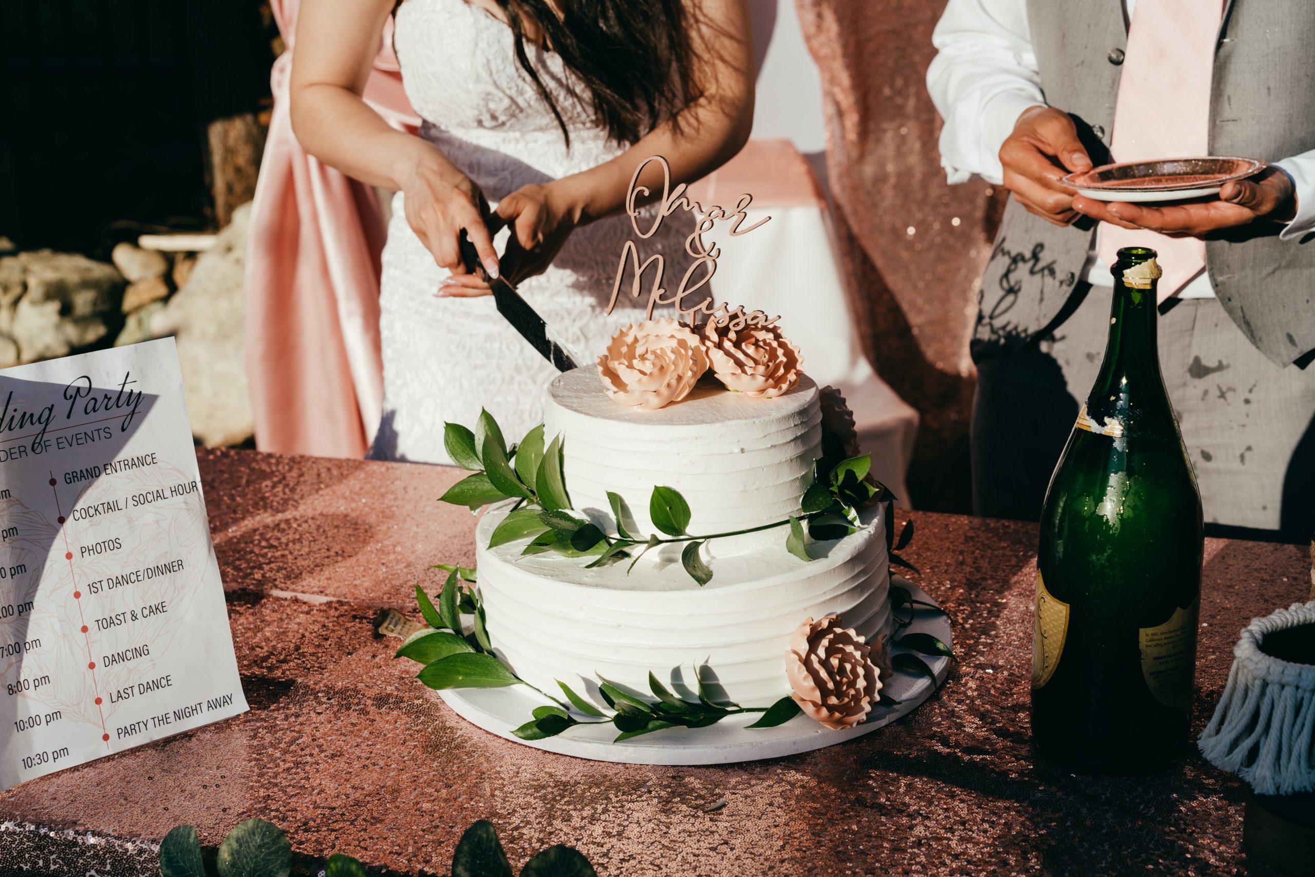 Hands of a bride cutting a wedding cake.