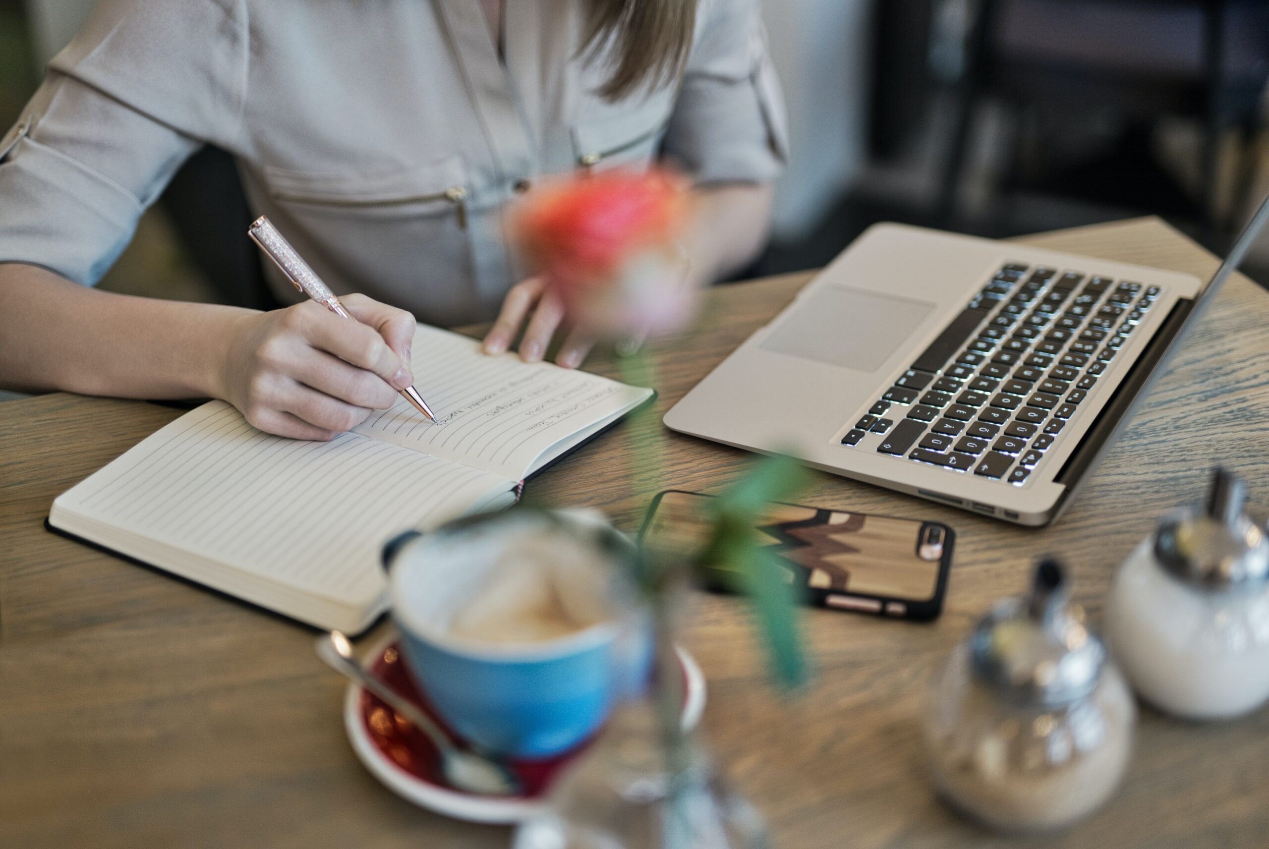 Woman writing next to laptop