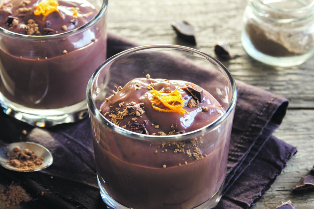 Chocolate Mousse topped with Orange Zest in glasses over wooden background close up 