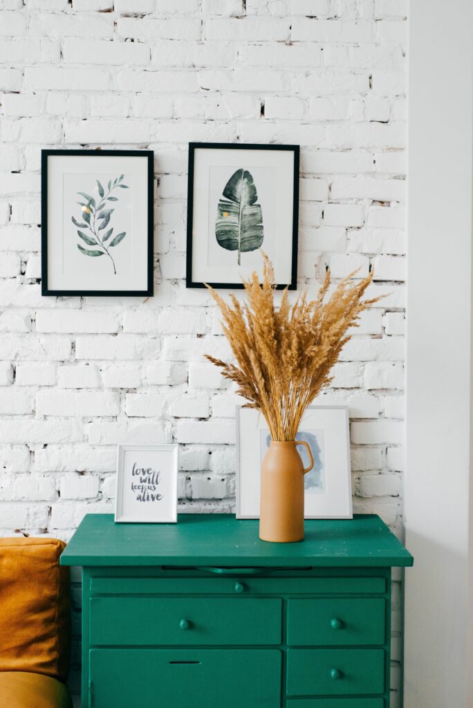 A green painted chest of drawers with white exposed-brick background 