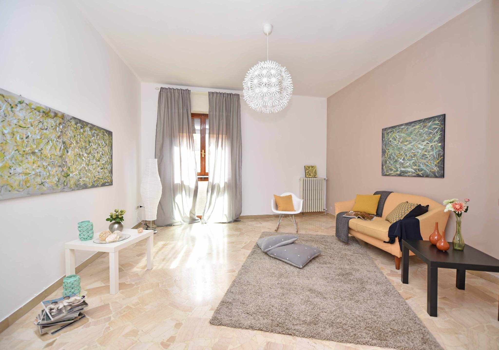 Living room in grey and pastel tones, with windows, grey curtains and two abstract paintings