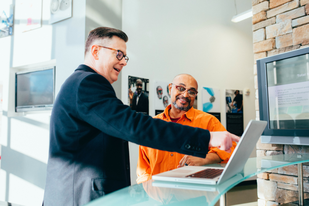 A manager shares a joke with his colleague during a productivity meeting.