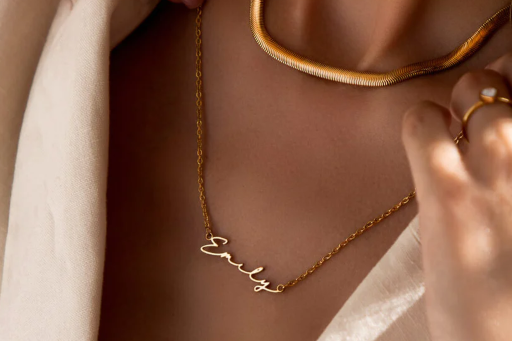 A gold Abbott Lyon Signature Name Necklace personalised with the lady's name who's wearing it.