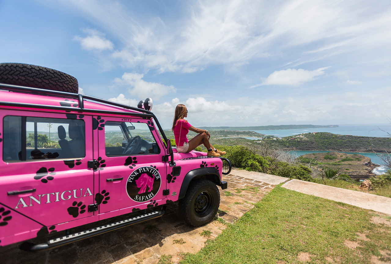 A Pink Panther Tour Guide takes a break from her duties and admires the views of Antigua while sitting on her pink jeep.
