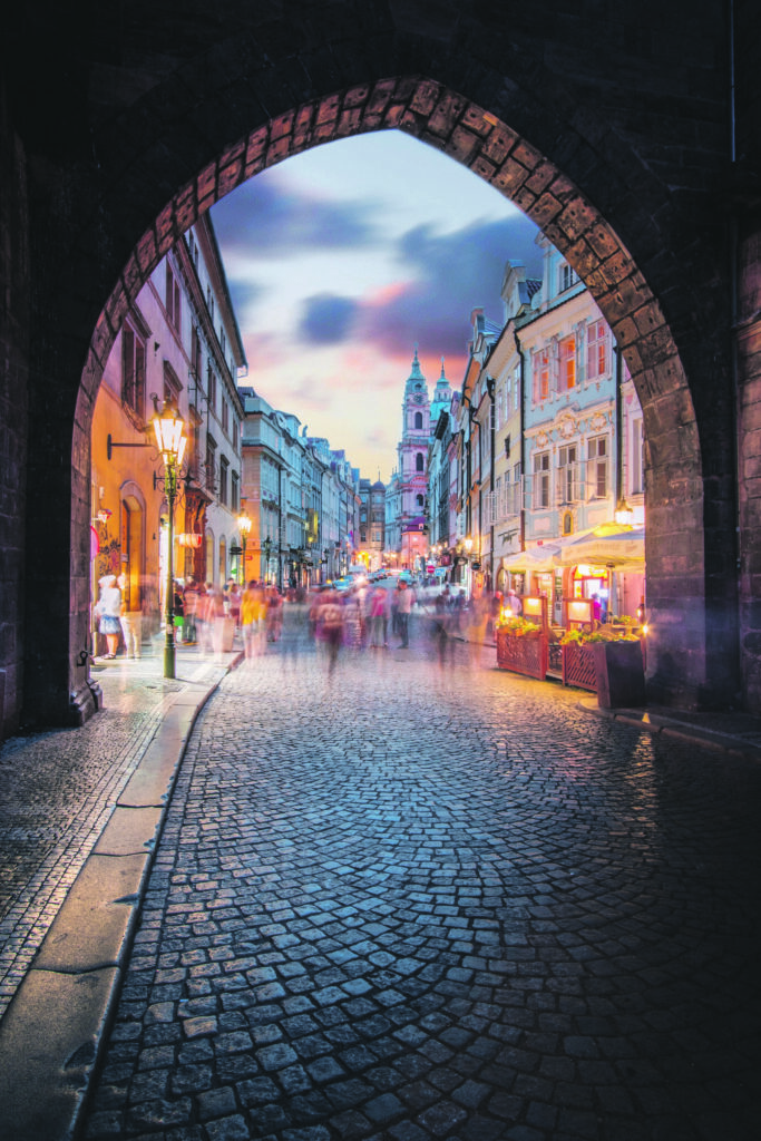 Framed by an archway, the entrance to Hradcany, Prague, during dusk.