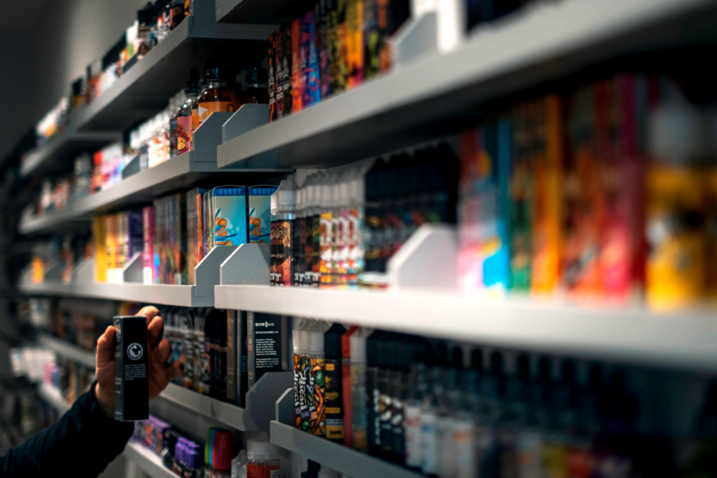 A hand taking an Elf Bar vape from a supermarket shelf.