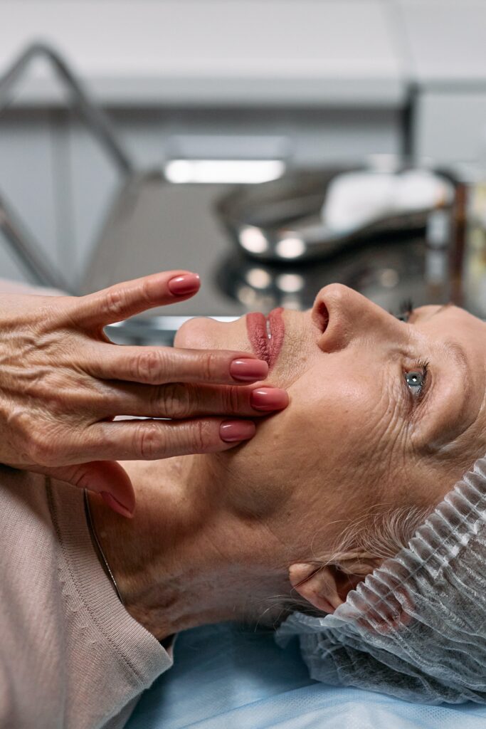 Elderly woman in surgical cap touching face