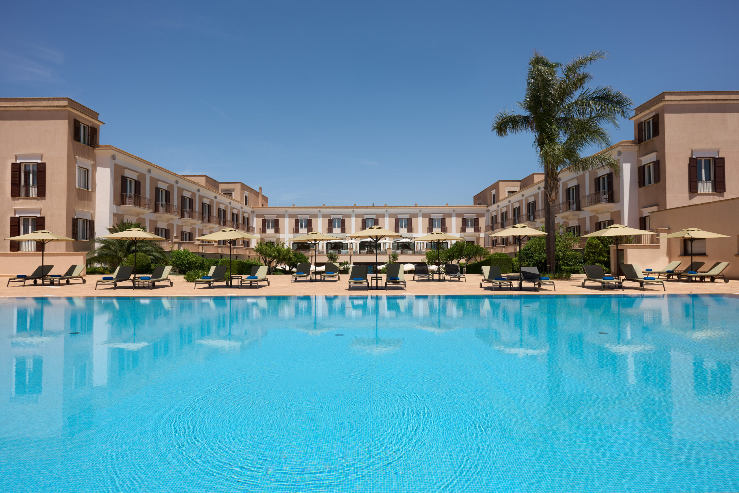 Hotel exterior with large pool and palm trees