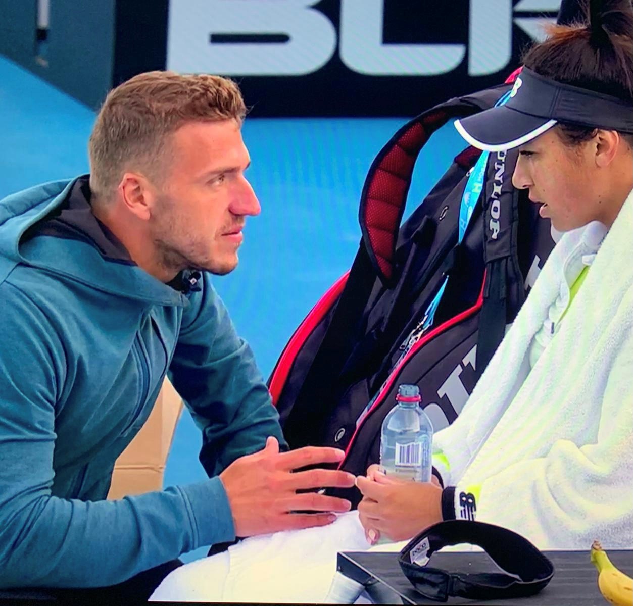 Professional tennis coach Alex Ward offers advice to a tennis player during a break.