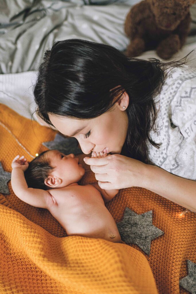 Mother cuddling with her newborn baby on bed