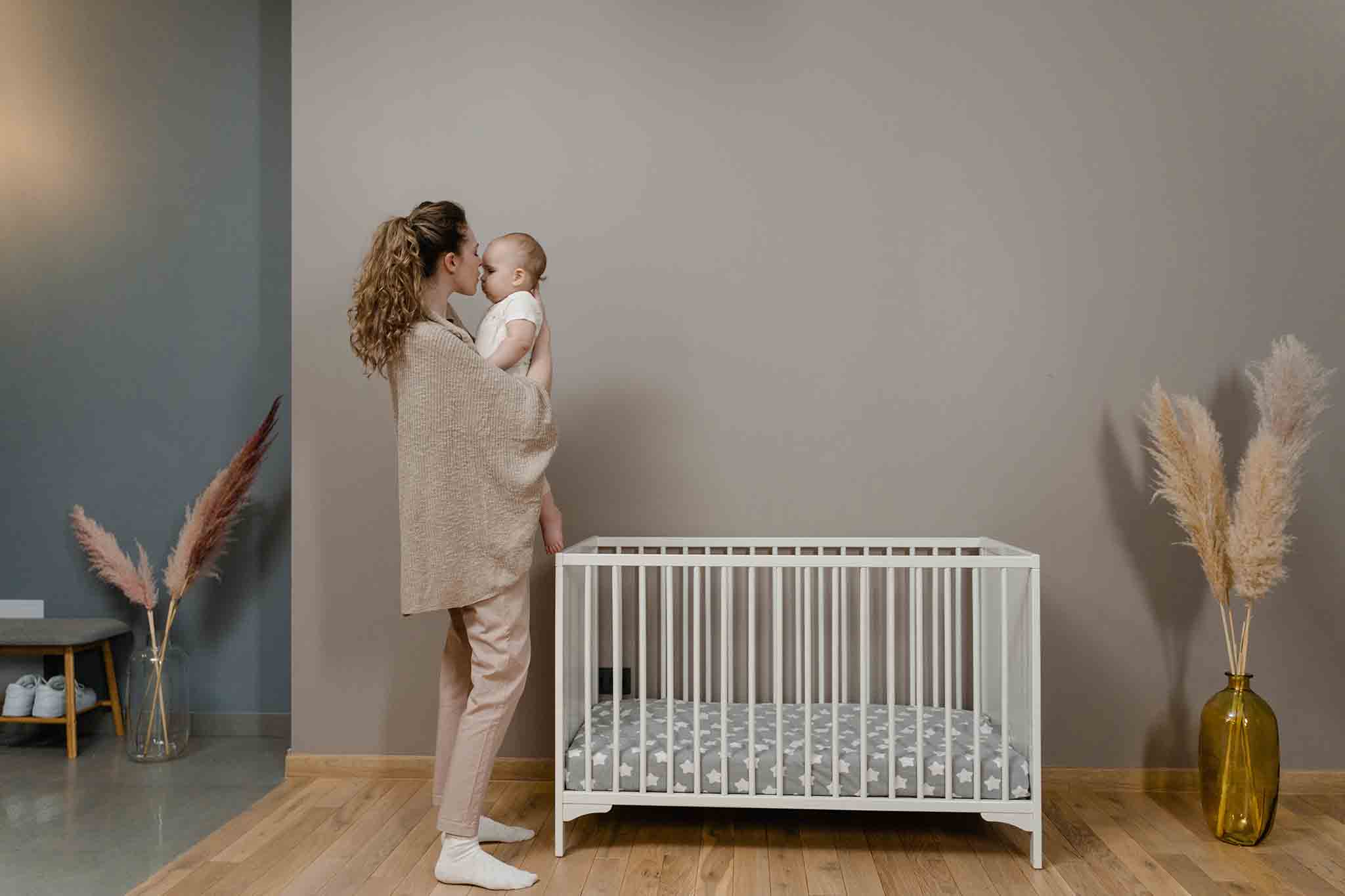 Mum with newborn standing in front of cot bed