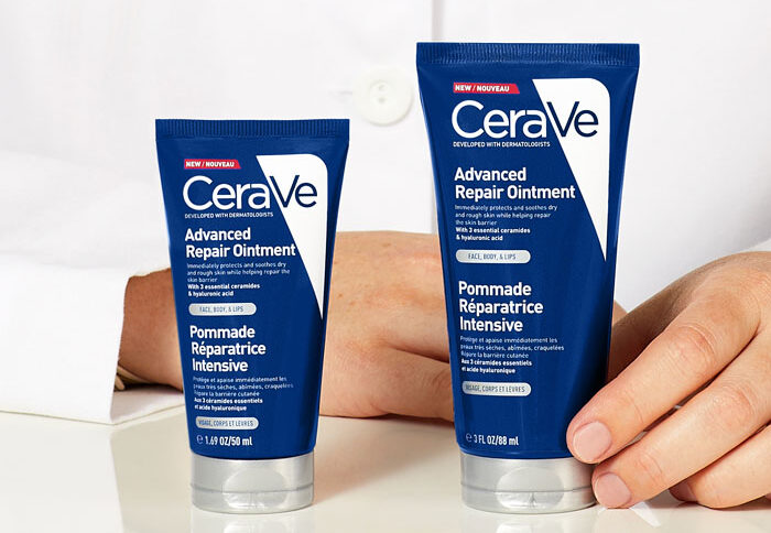 Two bottles of CeraVe Advanced Repair Ointment in front of a person wearing a lab coat