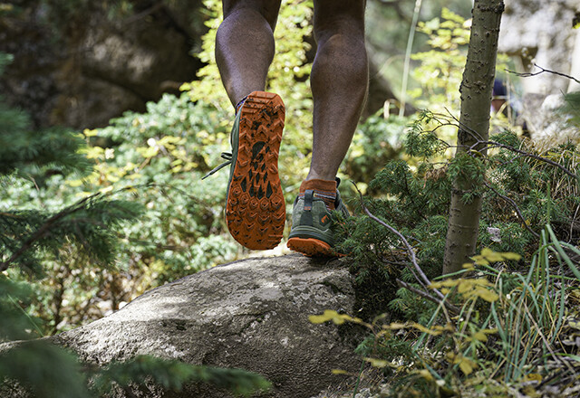 The feet of a man trail running on a rock
