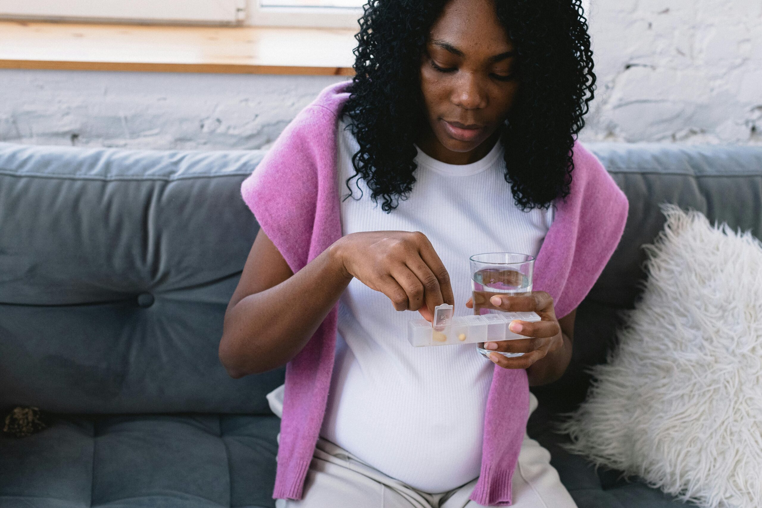 a pregnant woman takes supplements out of a pill box