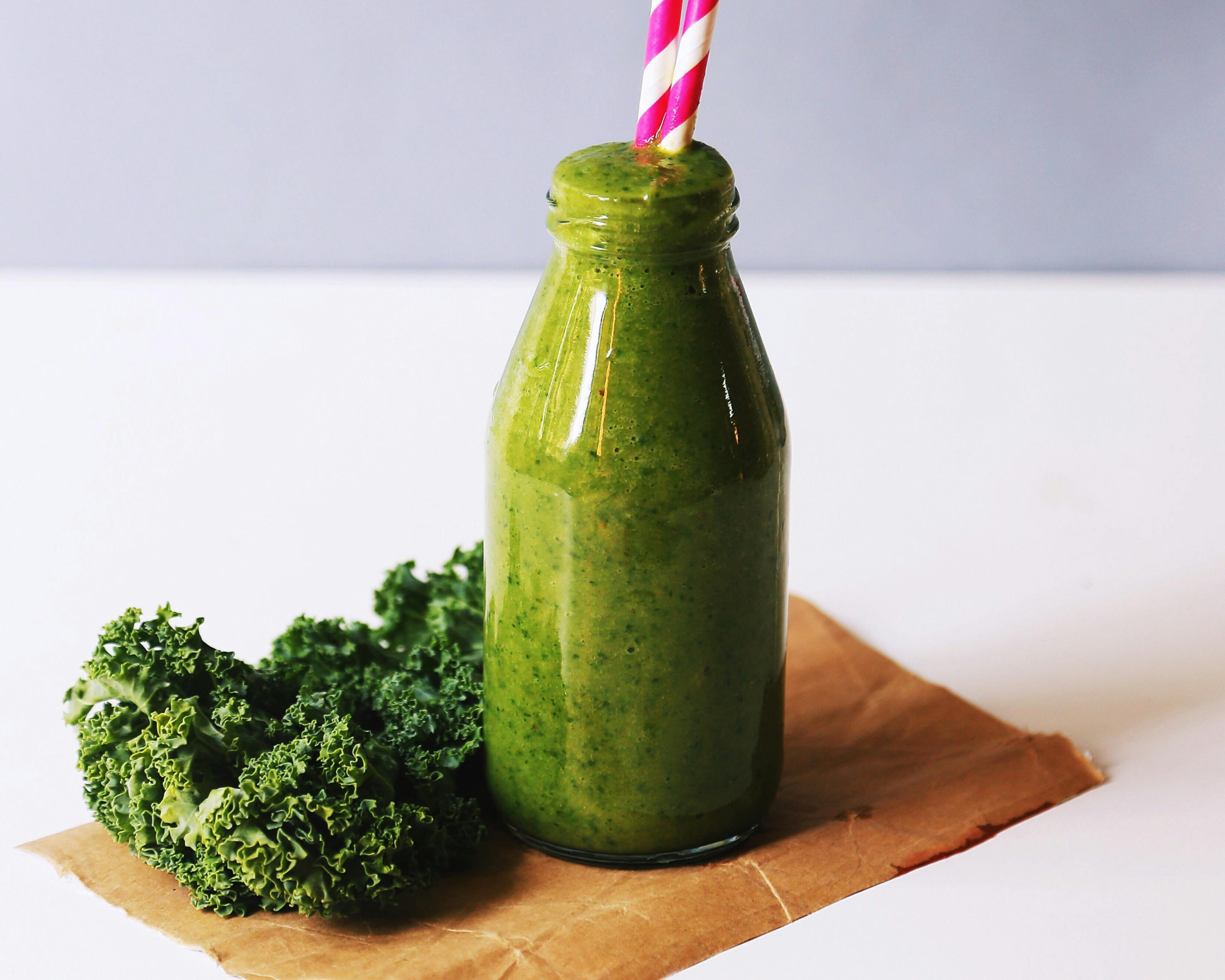Green juice with kale on wooden chopping board