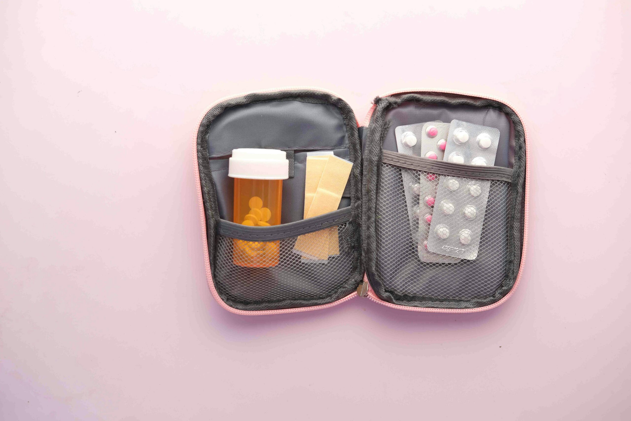 an open first aid kit against a pink background