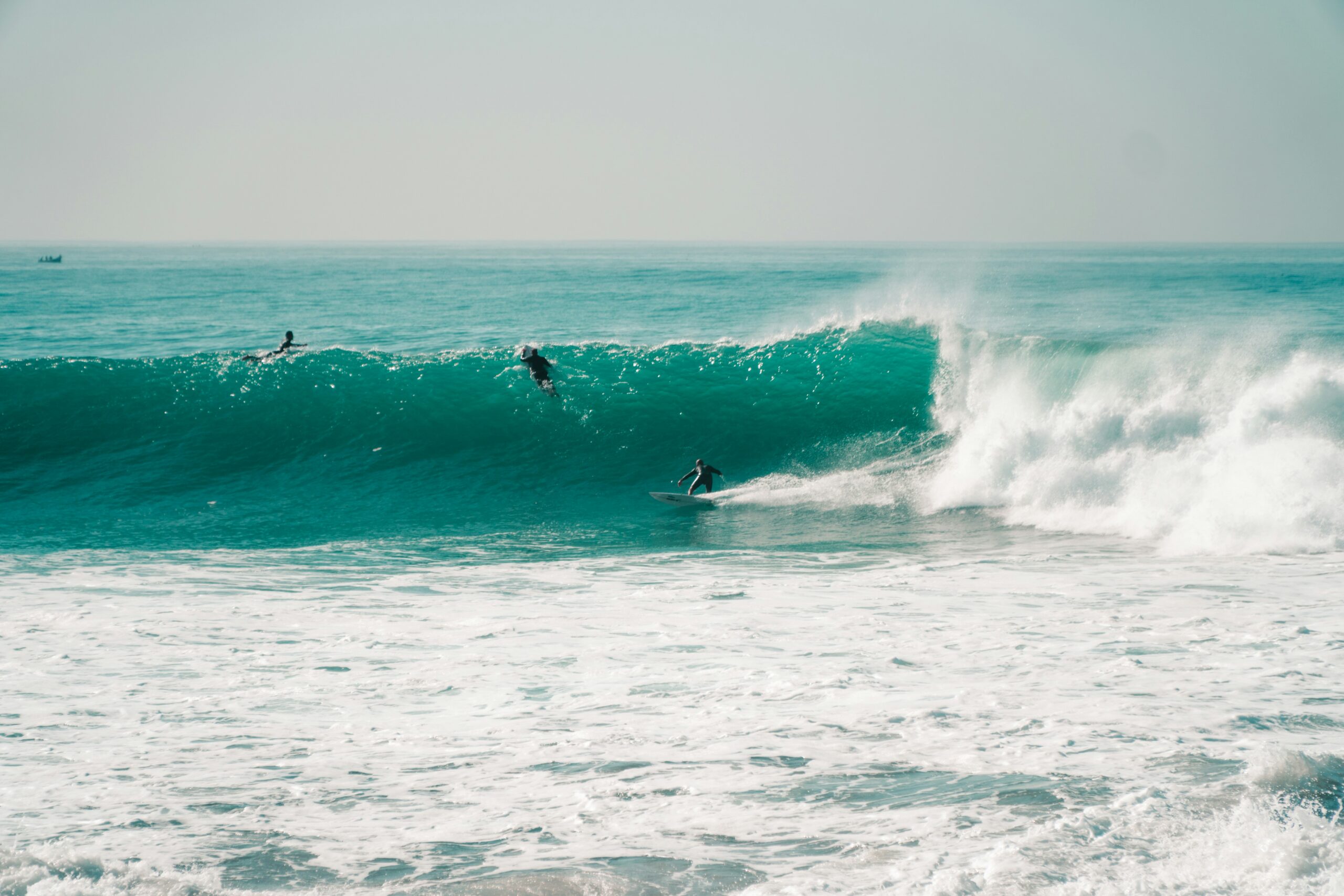 Three surfers ride a wave in Taghazout Bay beach