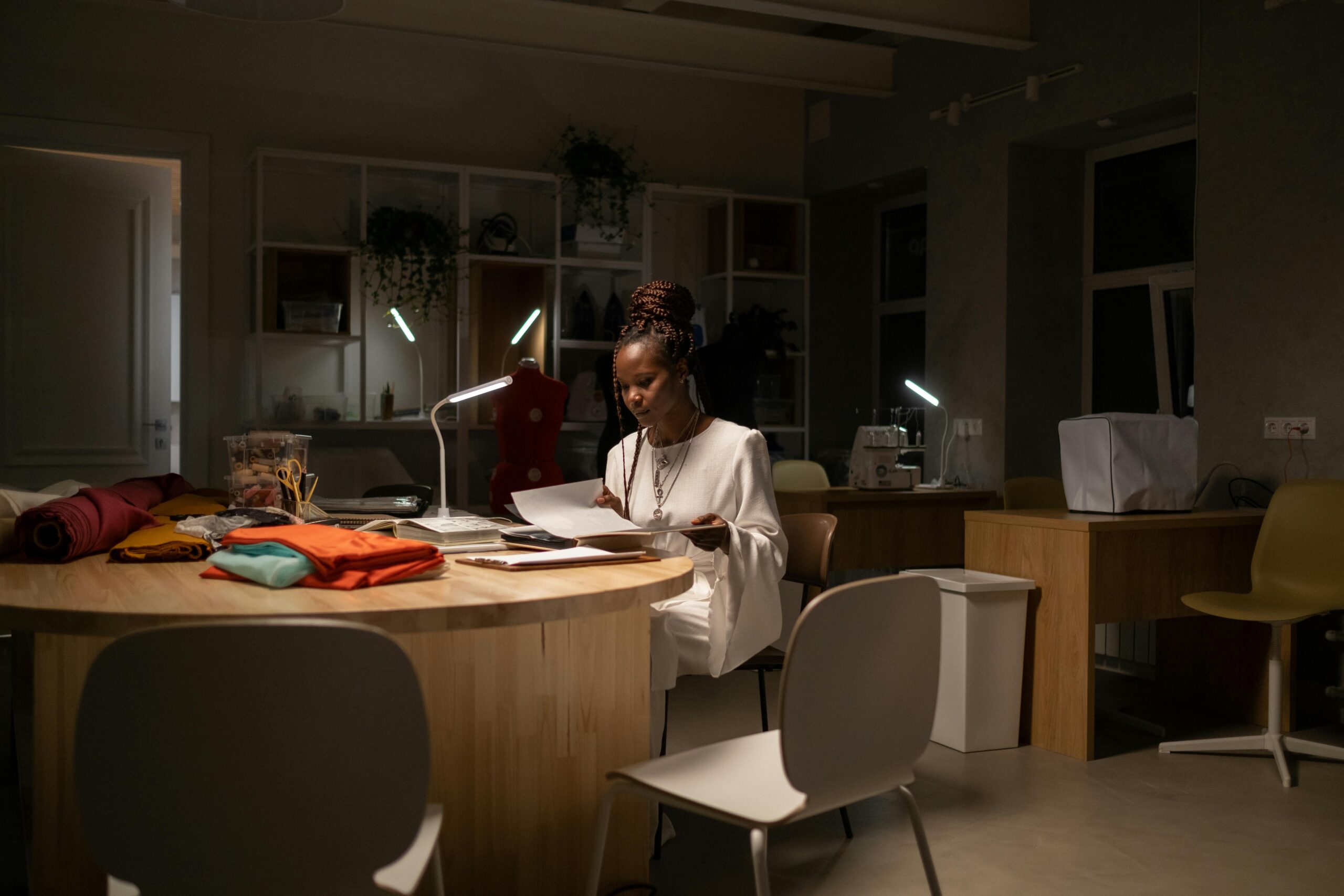 Young fashion designer looks tired while working late in sewing work space