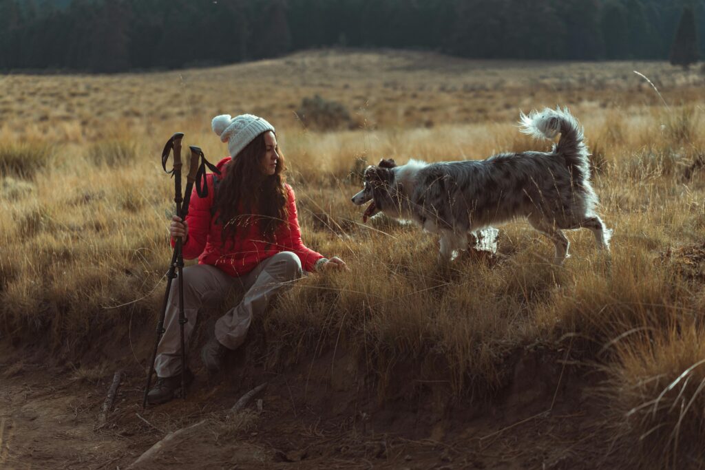 Hiker rests with her dog on a mountain trail.