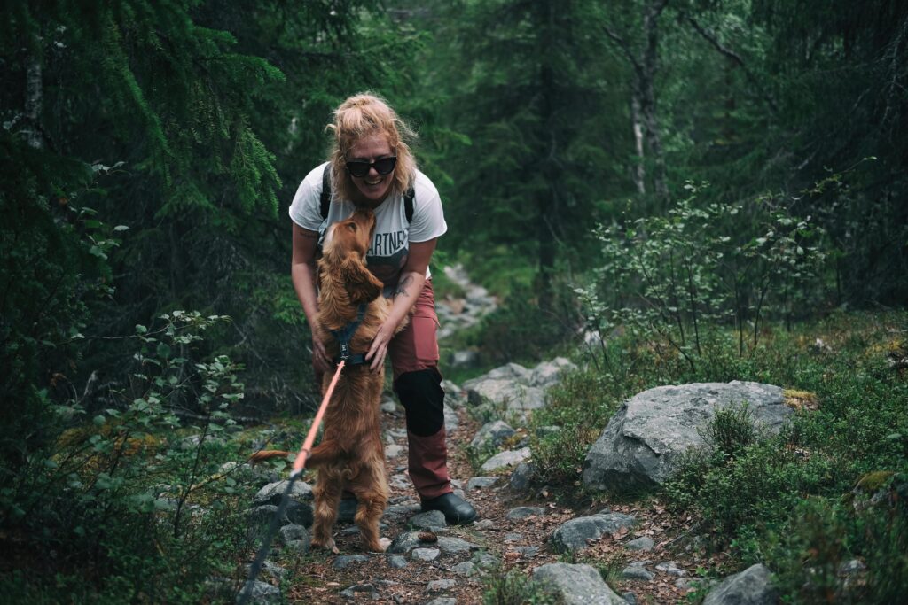 Hiker cuddles her dog on a woodland walk.