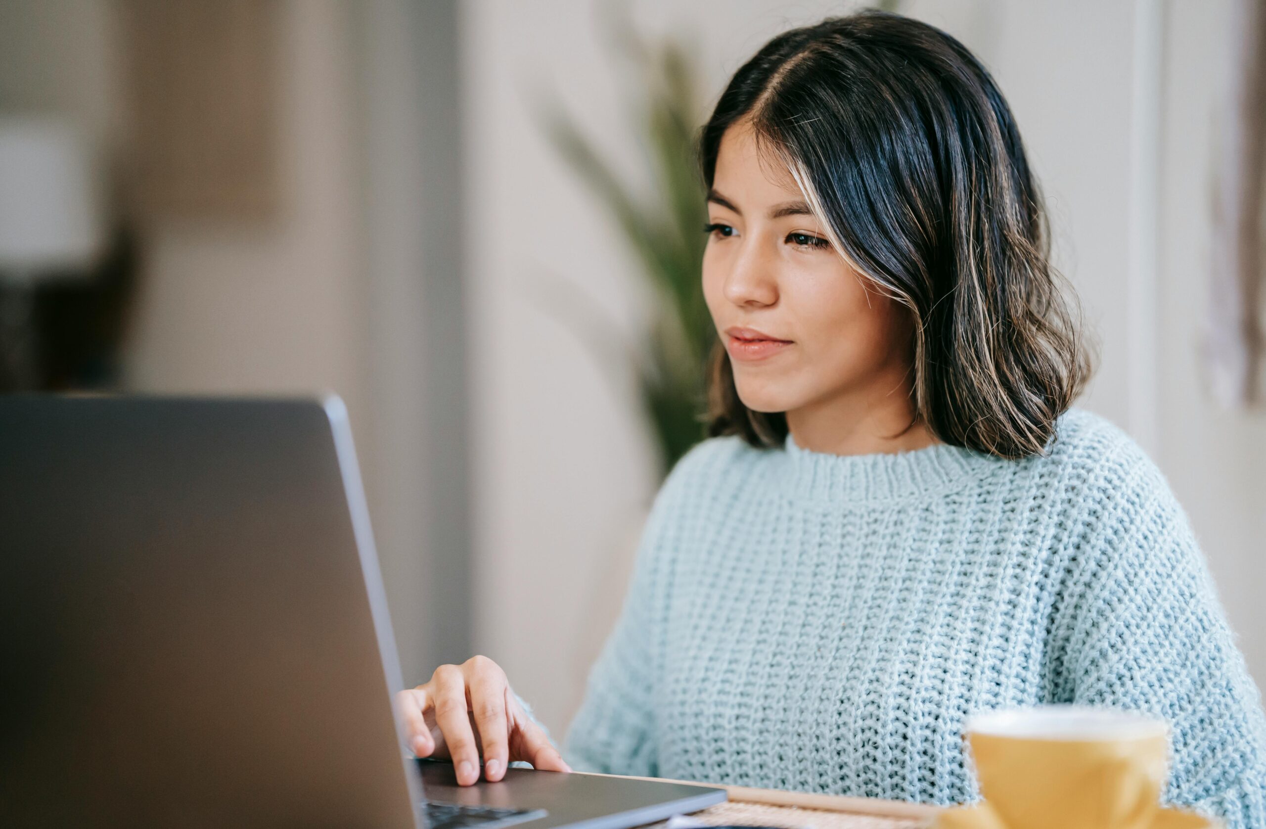 a woman sits in front of a a laptop looking focussed