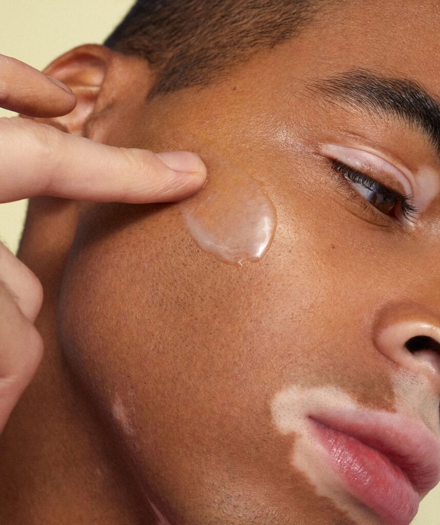 A black man with vitiligo swipes Byoma's Hydrating Serum across his face