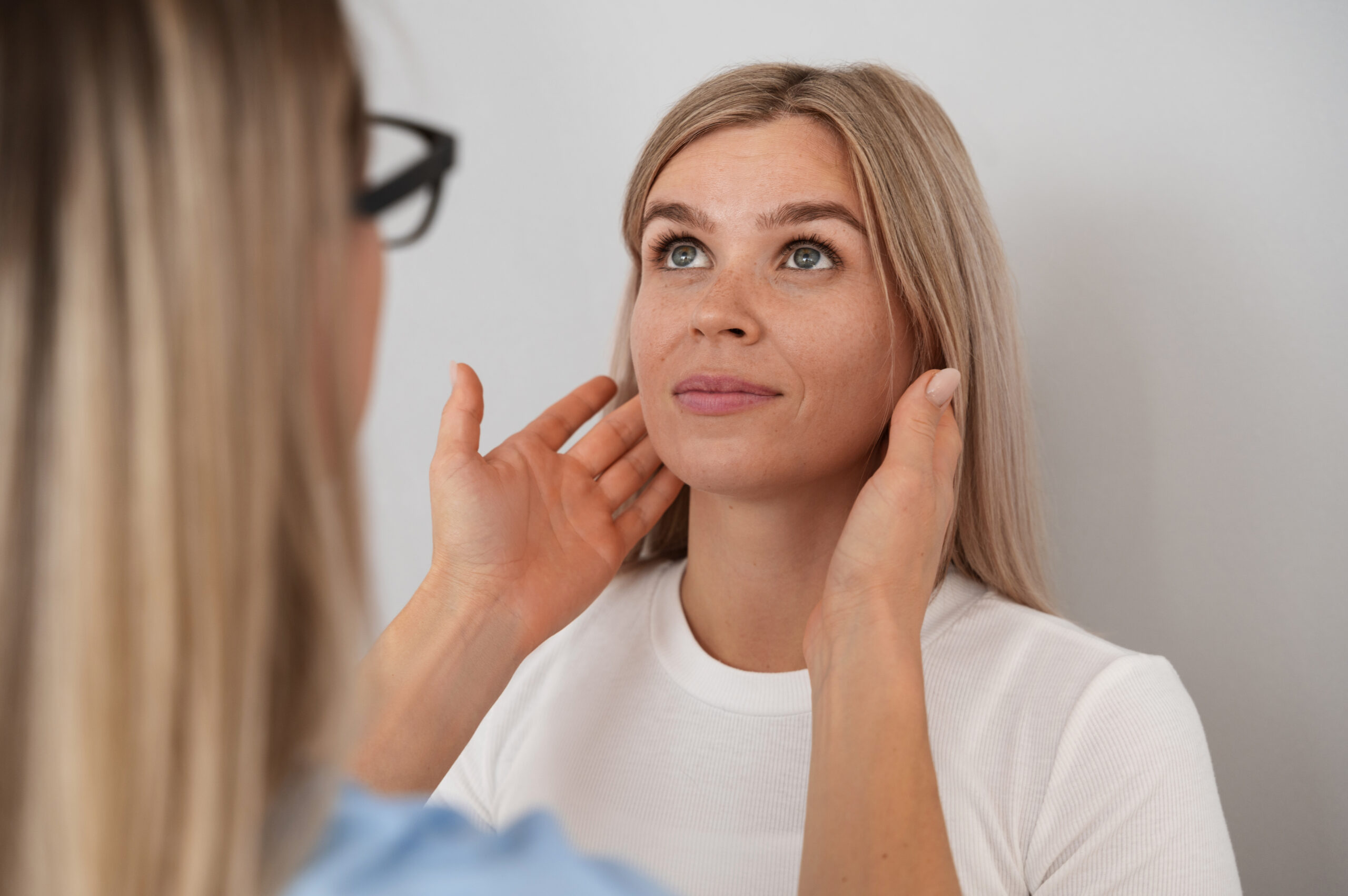 A clinician feels a woman's jawline 