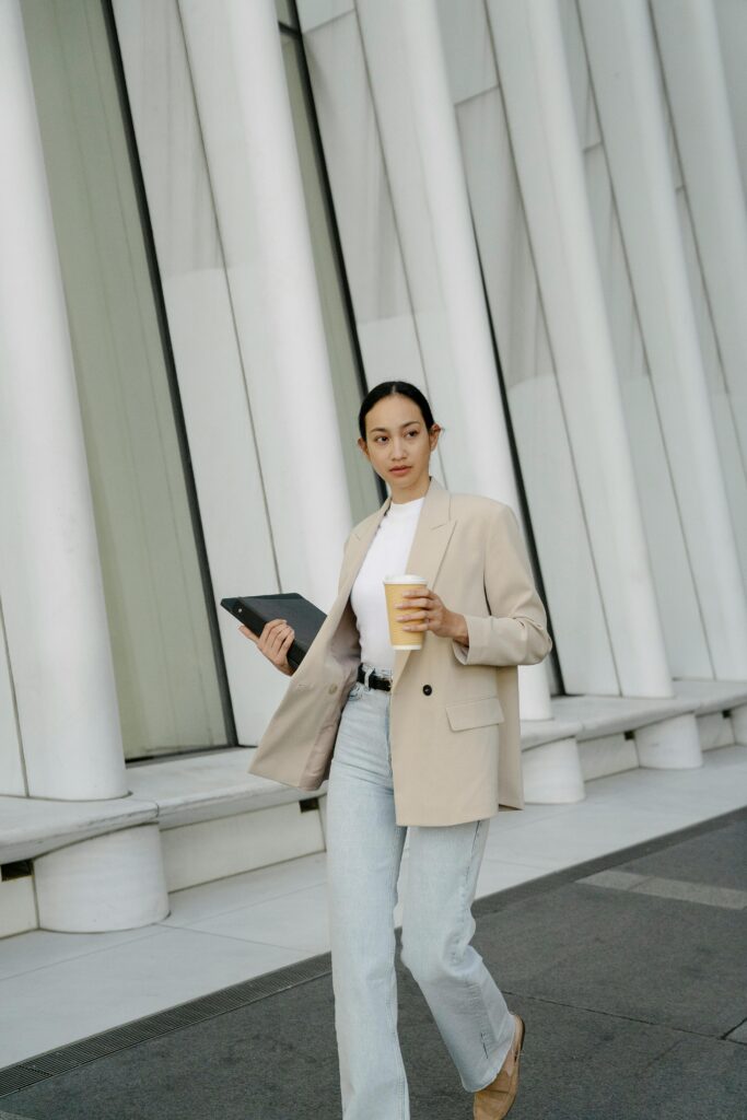 Woman walks with a coffee and laptop