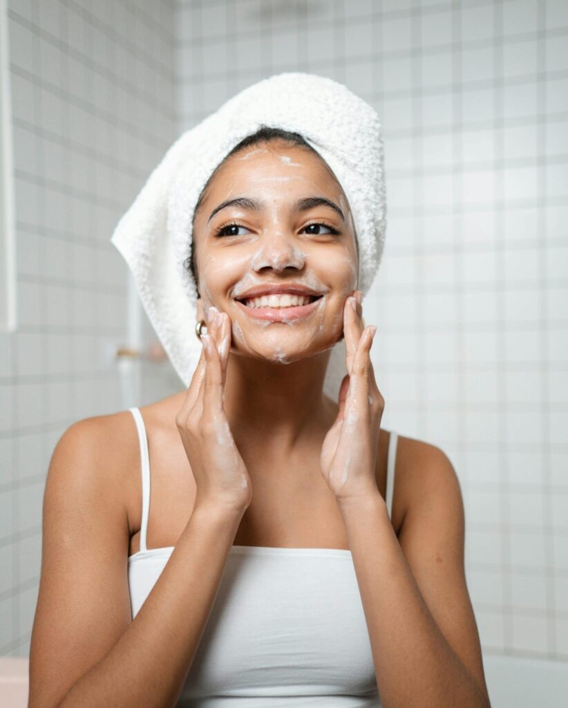 A woman stands in the bathroom washing her face with a milky cleanser