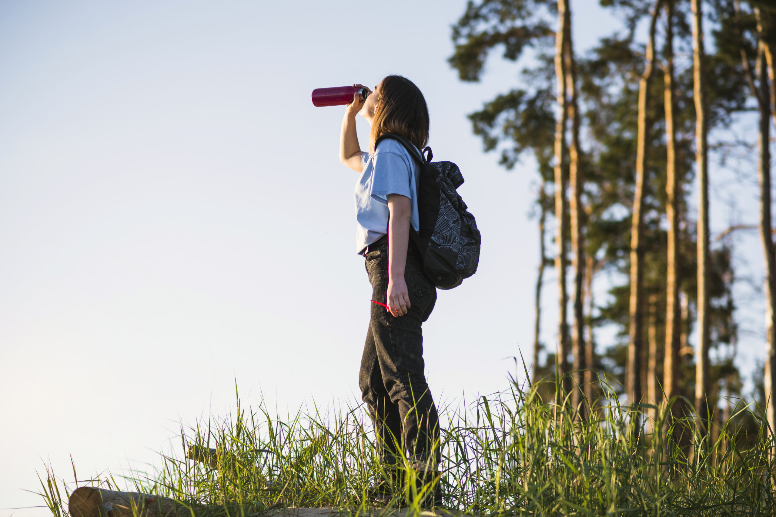 woman hiking alone and drinking from thermos