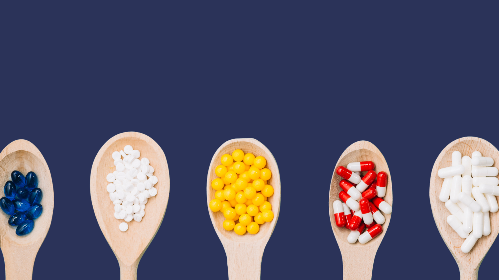 five wooden spoons with supplements on in front of a blue background 