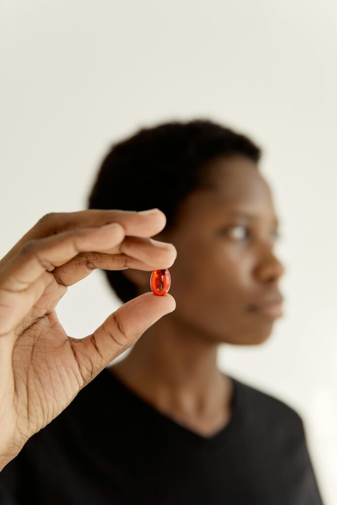 a black woman holds a red pill up to the camera