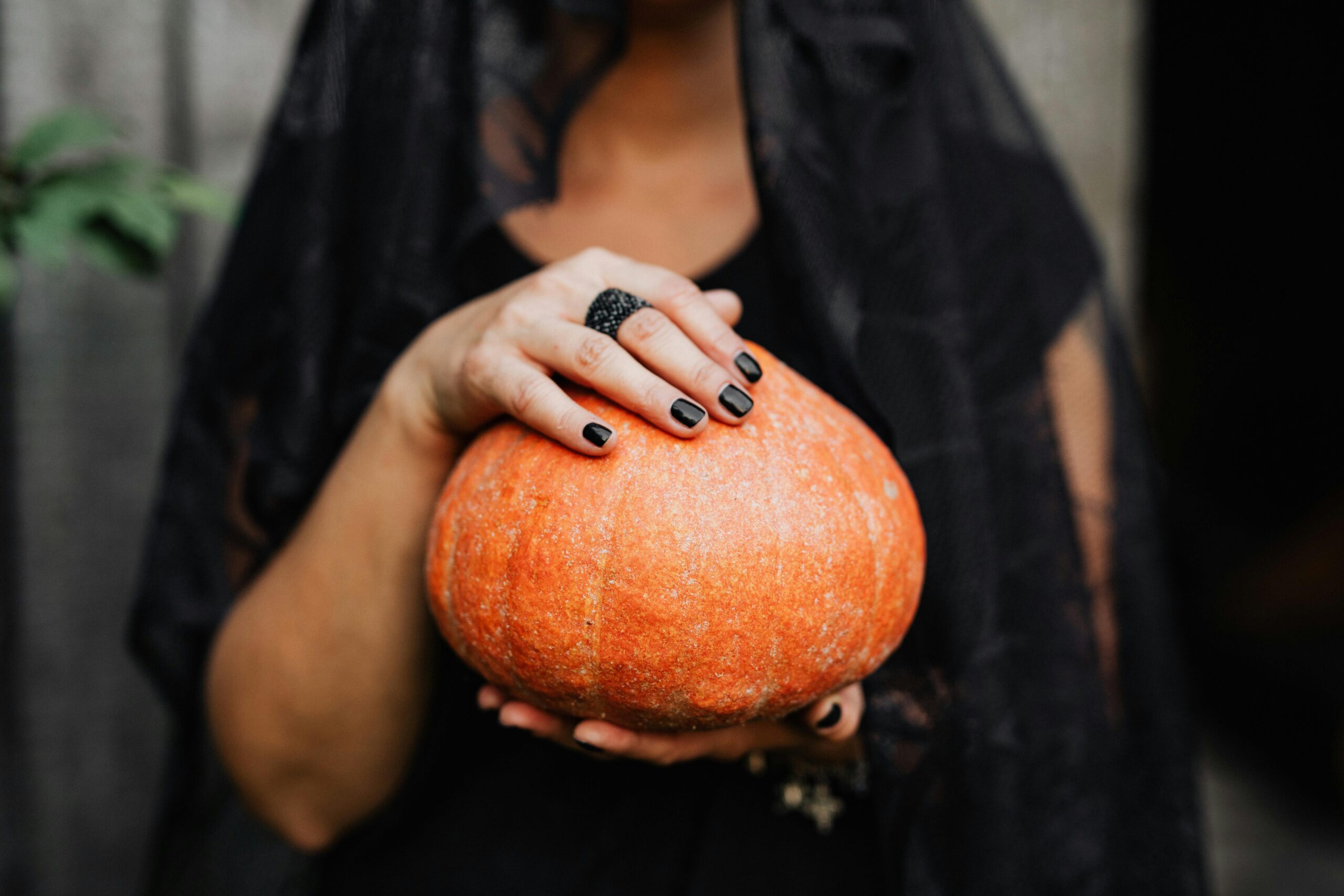 Woman with black nails holds a pumpkin