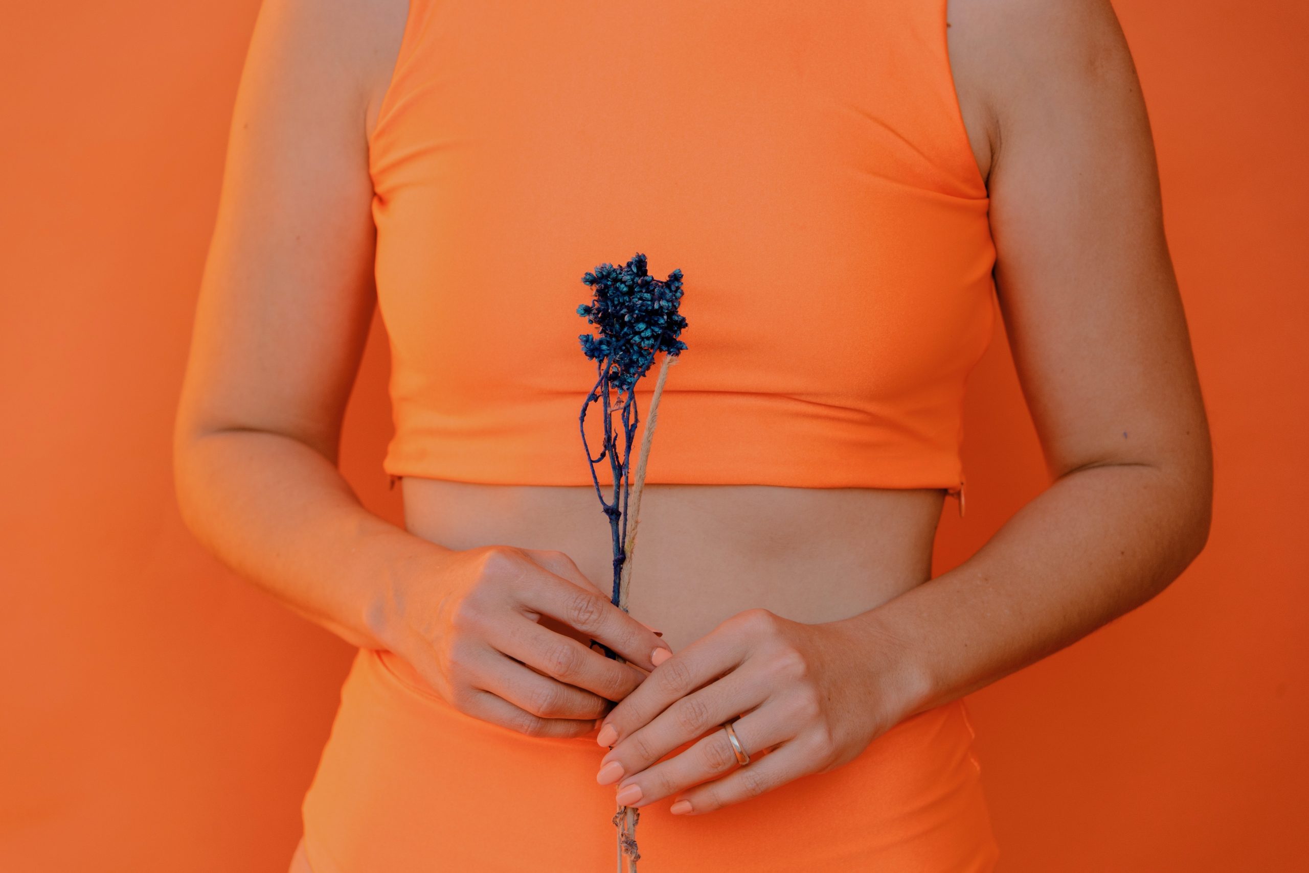 A woman holds a flower up in front of herself.