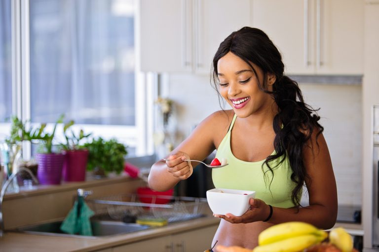 A healthy woman eating fruit for breakfast to boost her gut health.