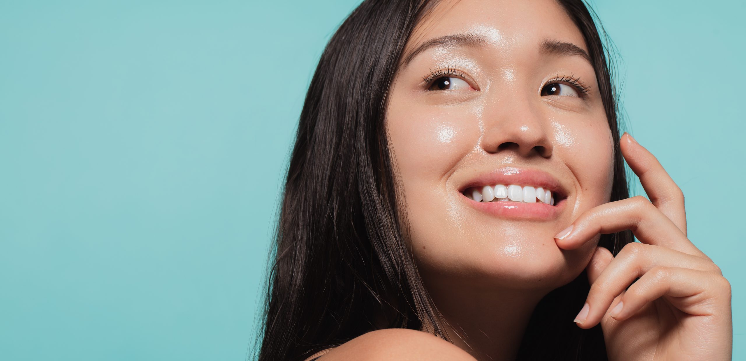 A woman smiling with beautiful glass skin.