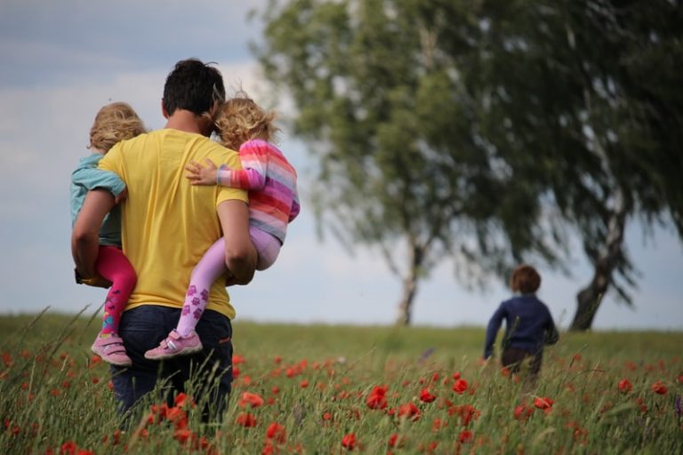 A father walks with his children through a field.