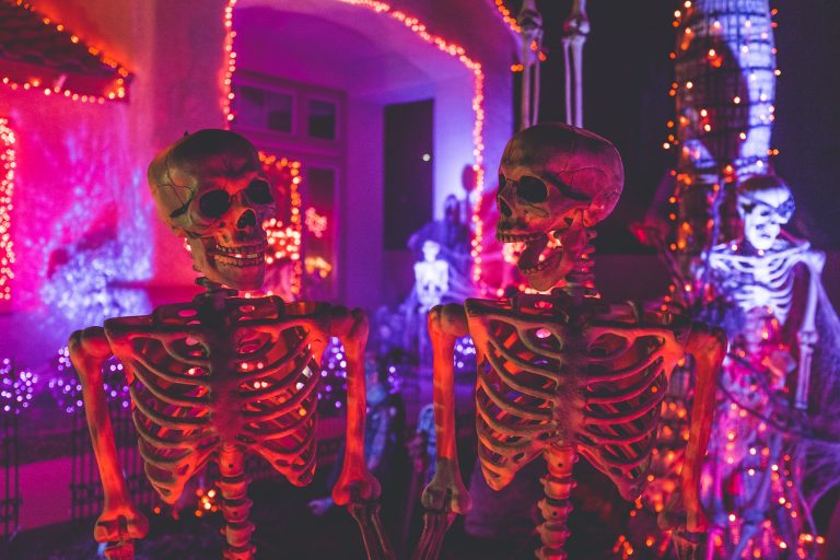 Two human skeletons stand guard at a Halloween party