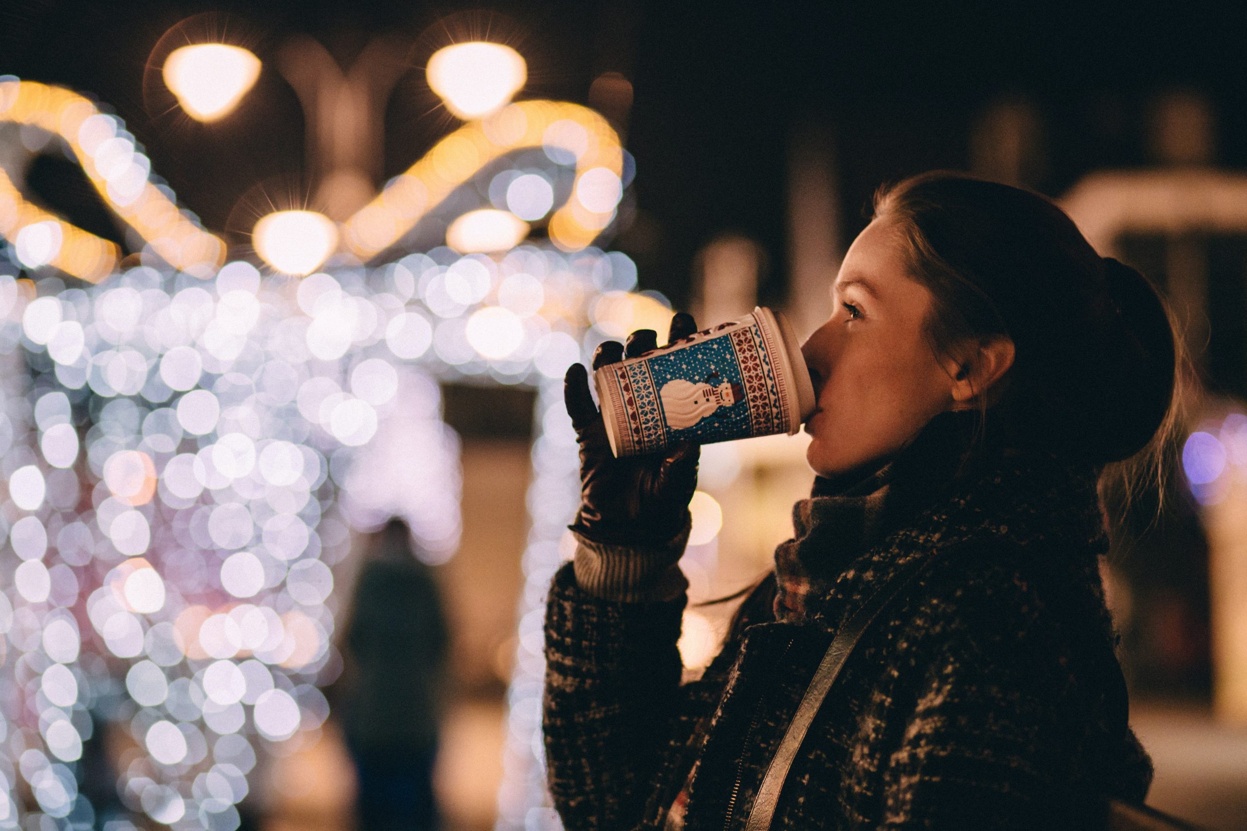 A woman sips a hot drink to stay warm at Kew Gardens's Christmas event