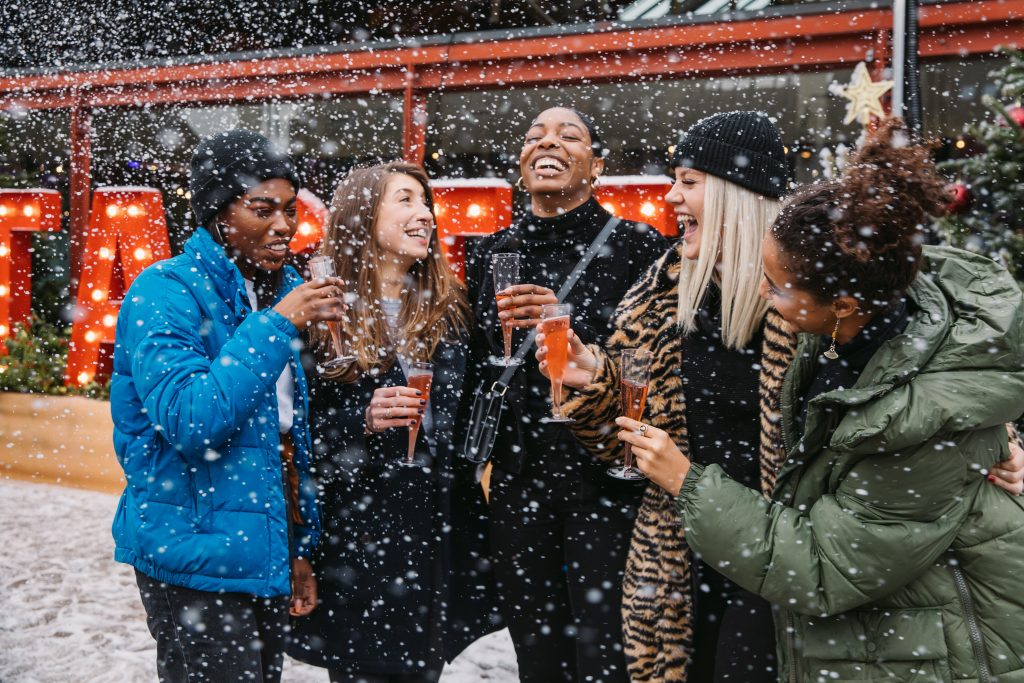 Five friends share a Christmas drink outside in the snow
