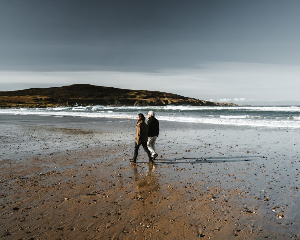A couple walk along the beach while the tide is out
