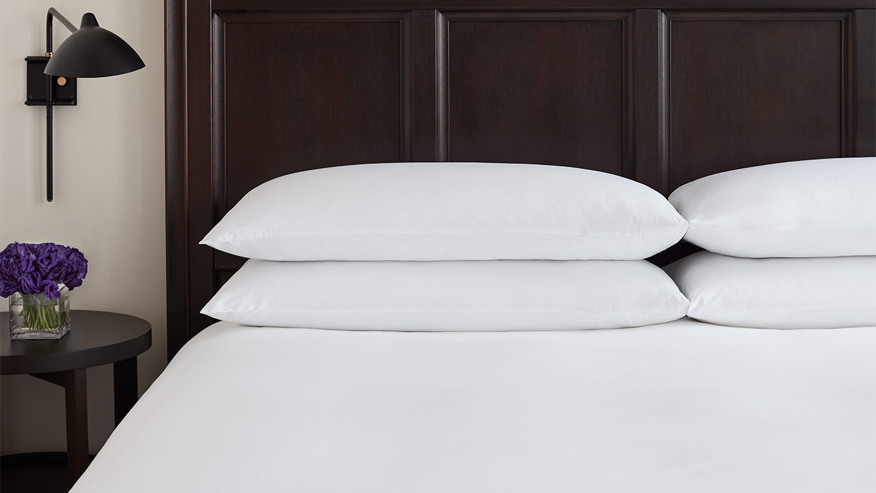 A black bed with white pillows and linen by EDITION Hotels