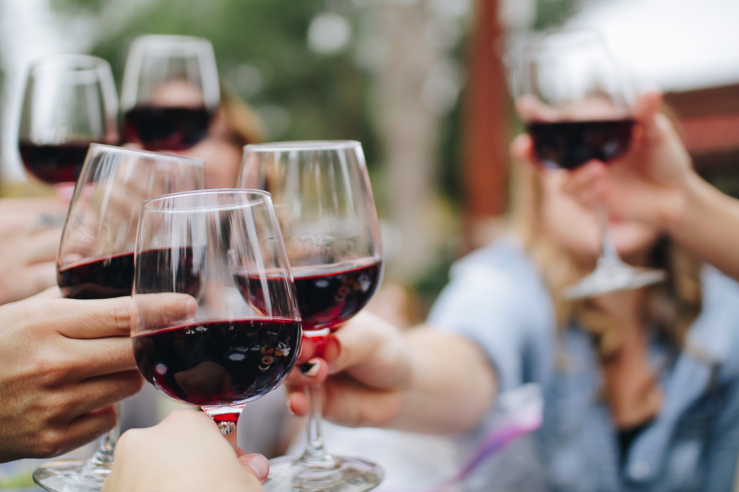 A group of friends make a toast with red wine