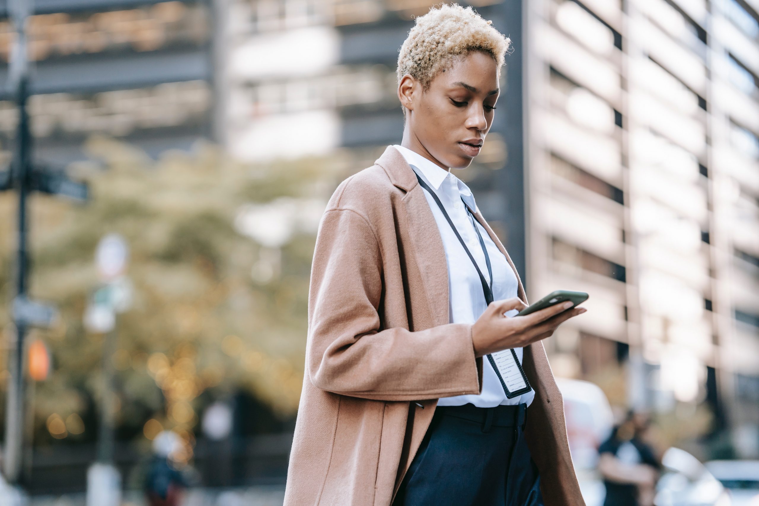 A smartly dressed businesswoman checks her wellness app while walking in the street