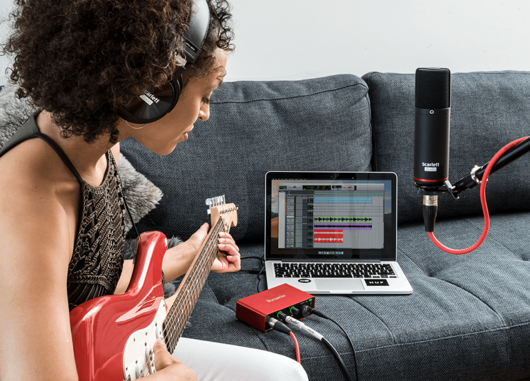 An aspiring guitarist records a song on her laptop with the Focusrite Scarlett Solo Studio