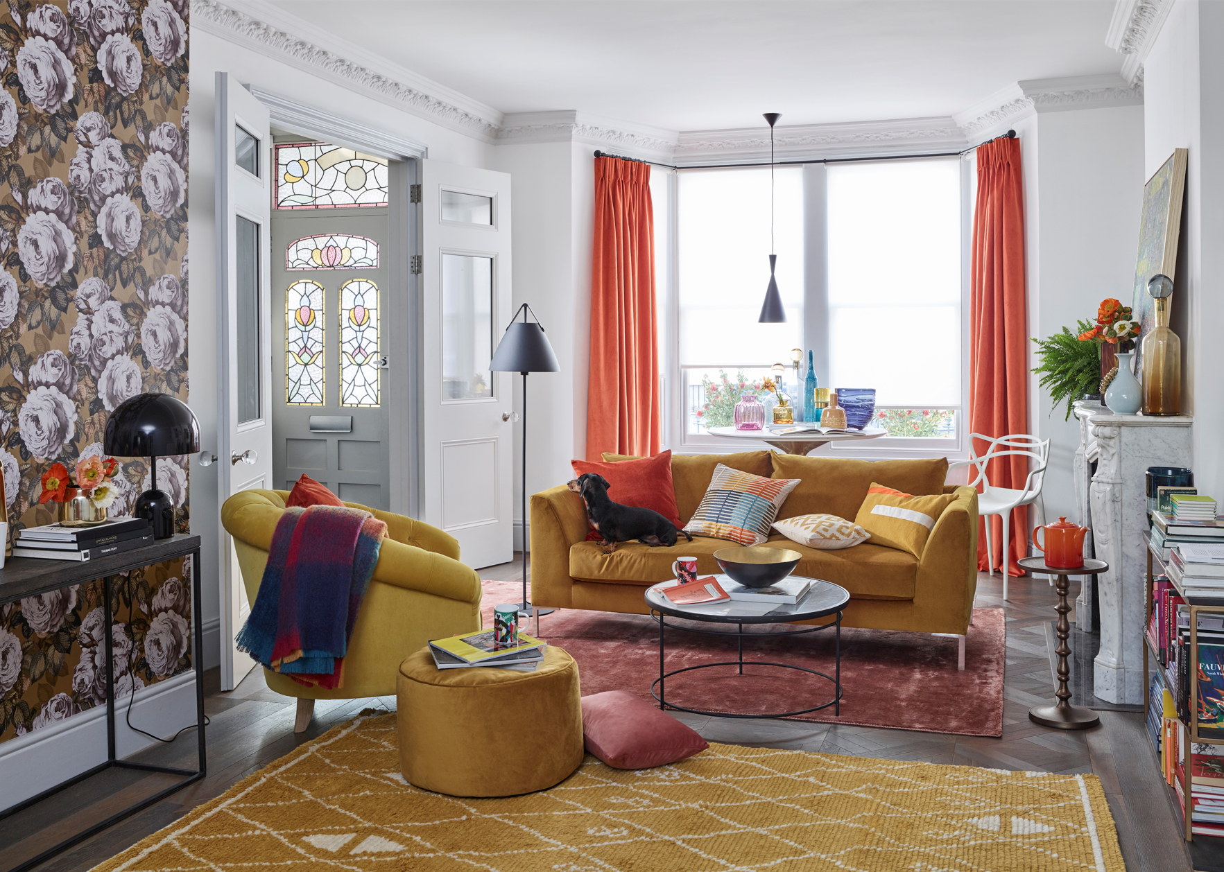 A cosy living room with ochre furniture and matching rug.