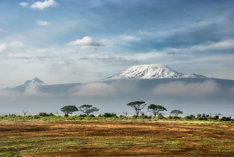 Mount Kilimanjaro rises out of the clouds in the distance.