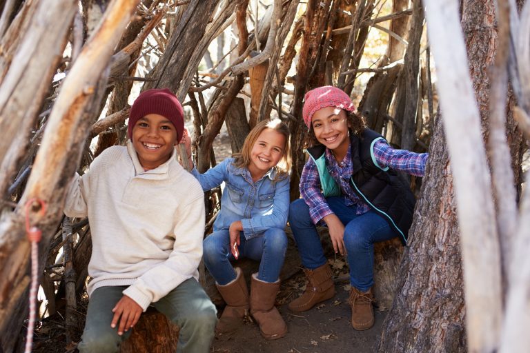 A group of children playing together in a forest camp.